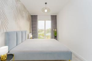 sypialnia z niebieskim łóżkiem i oknem w obiekcie Fredry 2 Apartament Liliowy w Kołobrzegu