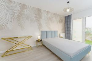 sypialnia z łóżkiem i ścianą z malowidłem w obiekcie Fredry 2 Apartament Liliowy w Kołobrzegu