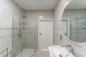 łazienka z prysznicem, umywalką i lustrem w obiekcie Fredry 2 Apartament Liliowy w Kołobrzegu +33 zdjęcia