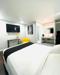 ein Hotelzimmer mit 2 weißen Betten und einem gelben Stuhl in der Unterkunft Hotel Villa Serena in El Cajon
