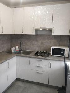 a kitchen with white cabinets and a sink and a microwave at Studio COMFORT on Golovna street in Chernivtsi