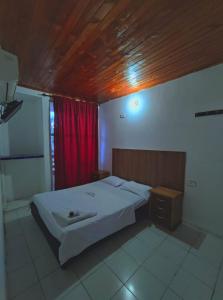 a bedroom with a bed and a red curtain at Hotel Venecia in Cereté