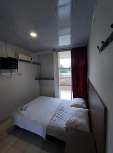 Hotel Venecia في Cereté: غرفة نوم بسرير ابيض مع نافذة
