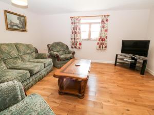 a living room with a couch and a tv at Sunnymead Cottage in Halwill