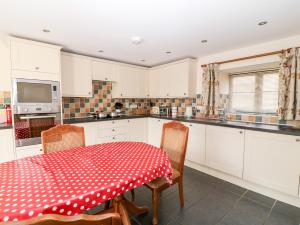 a kitchen with a red and white table and chairs at Sunnymead Cottage in Halwill