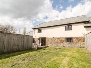 a stone house with a fence in a yard at Sunnymead Cottage in Halwill
