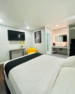 1 Schlafzimmer mit 2 weißen Betten und einem gelben Stuhl in der Unterkunft Hotel Villa Serena in El Cajon