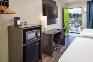 a hotel room with a desk with a tv and a bed at SureStay Hotel by Best Western San Diego Pacific Beach in San Diego