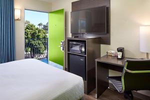 a hotel room with a bed and a desk with a television at SureStay Hotel by Best Western San Diego Pacific Beach in San Diego +14 photos