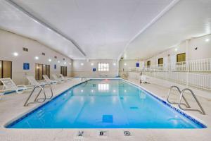 a large swimming pool in a building with chairs at Studio 6 Bartlesville - OK in Bartlesville