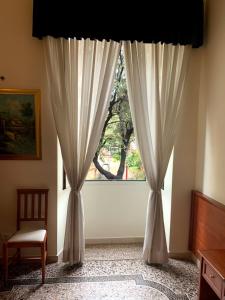 a window with white curtains and a chair in a room at Paramount in Rome