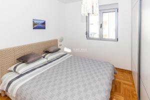 Bett in einem weißen Zimmer mit Fenster in der Unterkunft Luna Portonovi apartments in Herceg-Novi