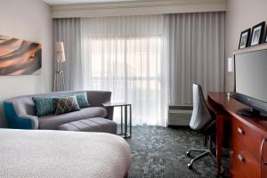 a hotel room with a bed and a couch and a television at Sonesta Select Newport Middletown in Middletown