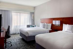 a hotel room with two beds and a desk at Sonesta Select Newport Middletown in Middletown