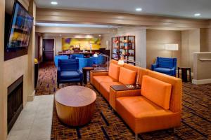 a hotel lobby with orange furniture and a fireplace at Sonesta Select Boston Danvers in Danvers