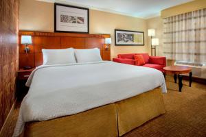 Habitación de hotel con cama grande y sofá rojo. en Sonesta Select Boston Danvers, en Danvers