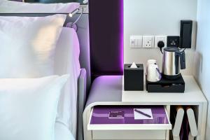 um quarto com uma cama e uma mesa com comodidades para preparar café em YOTEL Singapore Orchard Road em Singapura