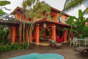 an orange house with a patio with a table and chairs at Pousada Villa do Sol in Itacaré
