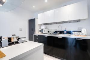 a kitchen with white cabinets and black appliances at Fairytale 2 Bedroom Apartment City Centre Free Parking in Birmingham