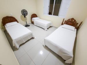two beds in a white room with a fan at Casa Canastra Bio in São Roque de Minas