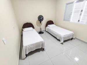 a white room with two beds and a fan at Casa Canastra Bio in São Roque de Minas