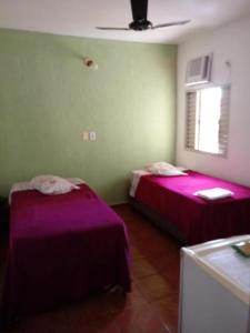 two beds in a room with purple sheets at Hotel Iguaçu in Botucatu