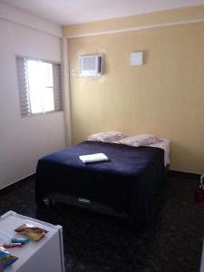 a bedroom with a bed with a blue blanket and a window at Hotel Iguaçu in Botucatu