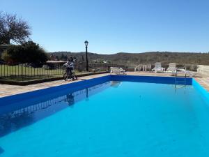 a person riding a bike next to a blue swimming pool at Cabañas La Escondida Casa De Campo 2 in San Antonio de Arredondo