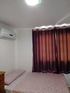 ein Schlafzimmer mit einem Bett mit einem roten Vorhang in der Unterkunft Apartamento temporada em Arraial do Cabo, Le Bon Vivant in Arraial do Cabo