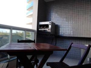 une table en bois avec des chaises et un four micro-ondes sur un mur dans l'établissement Apartamento temporada em Arraial do Cabo, Le Bon Vivant, à Arraial do Cabo