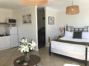 a bedroom with a bed and a table with a vase of flowers at Serendipity Adorable Tairua Studio in Tairua
