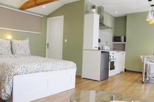 Cet appartement comprend une chambre avec un lit blanc et une cuisine. dans l'établissement Saint Etienne : appartement Châteaucreux 40 M2, à Saint-Étienne