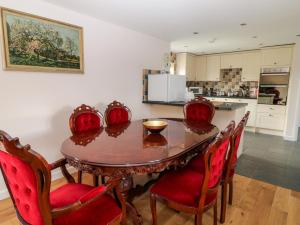 a kitchen with a wooden table and red chairs at Honeysuckle Cottage in Beaworthy