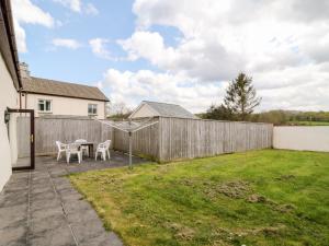 a backyard with a fence and a table and chairs at Honeysuckle Cottage in Beaworthy