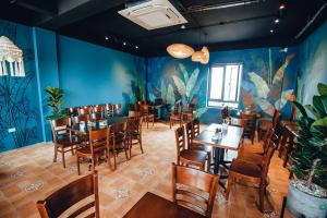 a restaurant with tables and chairs and a blue wall at Galvin Hotel in Sầm Sơn