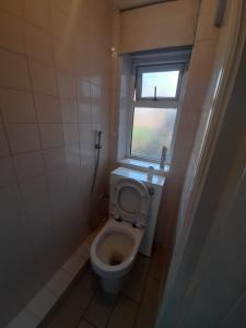 a small bathroom with a toilet with a window at Melverley House in Manchester