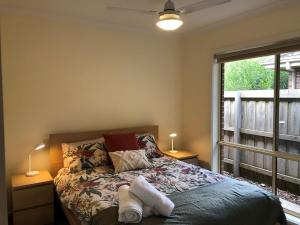 a bedroom with a bed with two lamps and a window at Woodland Heath Escape in Inverloch