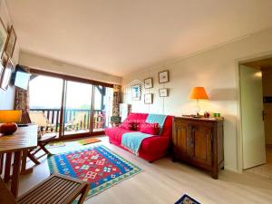 uma sala de estar com um sofá vermelho e uma mesa em Le Yearling C.L.S Deauville em Deauville