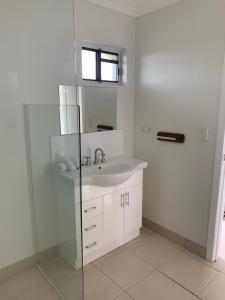 a bathroom with a sink and a glass shower at Airlie Beach Apartments in Airlie Beach +41 photos