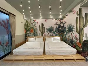2 Betten in einem Zimmer mit einem Wandbild von Kaktus in der Unterkunft 墾丁宜庭海景親子民宿 in Checheng