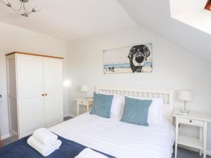 a bedroom with a bed with a dog picture on the wall at Isallt Cove in Trearddur