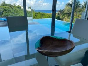 a wooden bowl on a glass table with a view of the ocean at Luxury Villa Cascada- infinity oceanview pool and elevator in Isla Mujeres