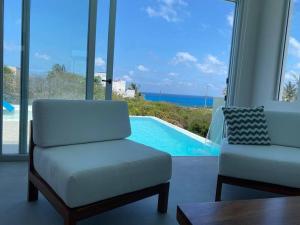 a living room with a couch and a chair and a pool at Luxury Villa Cascada- infinity oceanview pool and elevator in Isla Mujeres
