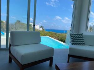 sala de estar con sofá, silla y piscina en Luxury Villa Cascada- infinity oceanview pool and elevator, en Isla Mujeres
