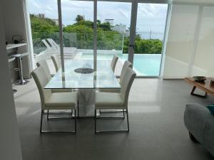 a dining room with a glass table and white chairs at Luxury Villa Cascada- infinity oceanview pool and elevator in Isla Mujeres