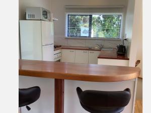 a kitchen with a wooden table and a white refrigerator at PACIFIC PARADISE COTTAGE in Tutukaka