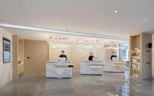 a lobby with three people sitting at desks with laptops at Atour Hotel Jinan High-Speed East Railway Station in Jinan