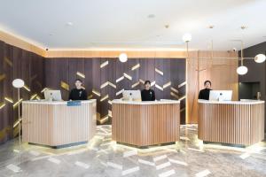 a lobby with three people sitting at desks with laptops at Atour Hotel Ningbo Jishi Harbor Outlets in Ningbo