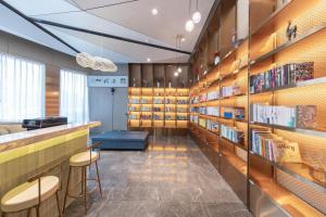 una biblioteca con estanterías de madera, taburetes y libros en Atour Hotel Kunming International Trade Center, en Kunming
