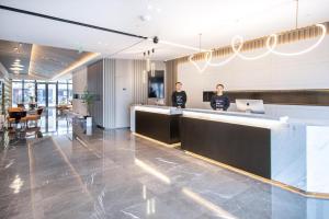 two people standing at a counter in a lobby at Atour Hotel Yuzhong Yuci Incity in Jinzhong